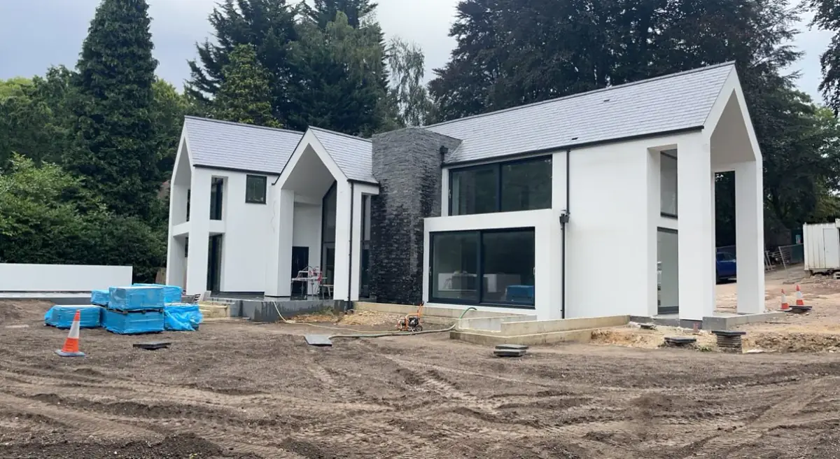 A new white and grey house with large glazing, nearing completion in Surrey